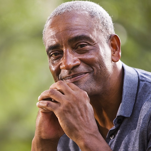 Elderly man smiling with his chin resting on his hands Elderly man smiling with his chin resting on his hands
